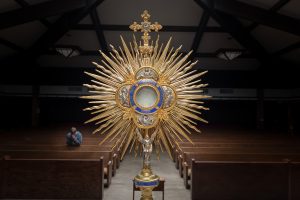 Jesus in the Monstrance with a man praying in the pew